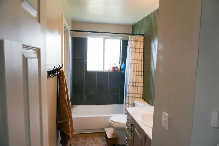 Full bathroom featuring a white bathtub, dark-tiled shower surround, and a single window