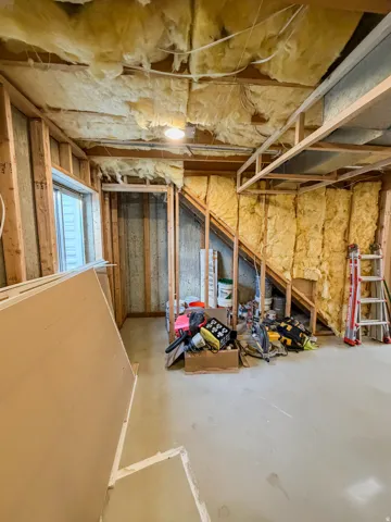 Unfinished interior space featuring exposed wood framing, ceiling insulation, and a concrete floor