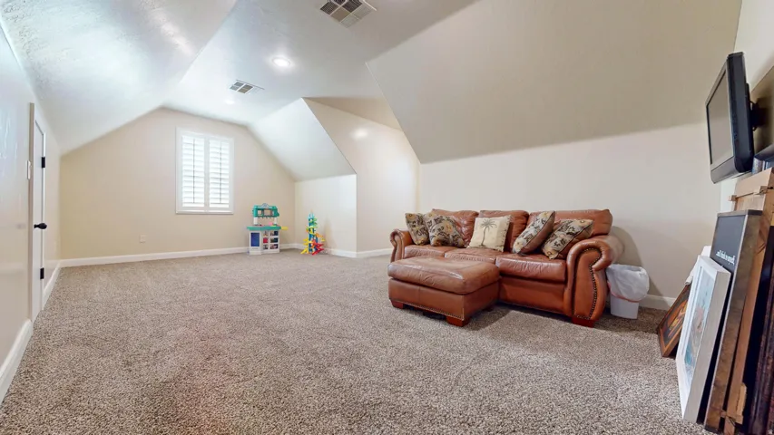 Carpeted room with sloped ceilings, recessed lighting, and a window with white shutters