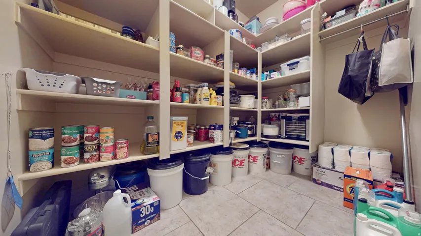 Custom built-in shelving, extensive storage capacity, organized corner shelving, additional hanging storage, and tiled flooring