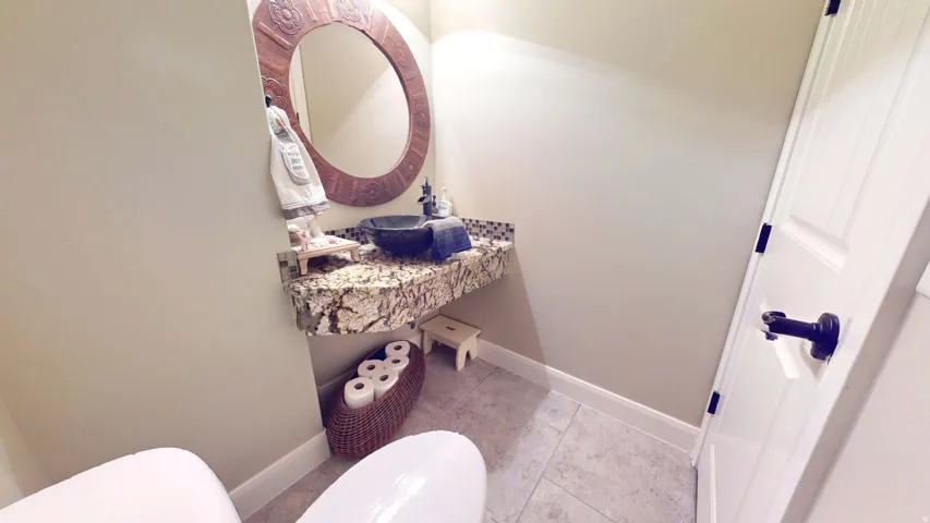 Floating vanity with a granite countertop, vessel sink, and an ornate framed mirror