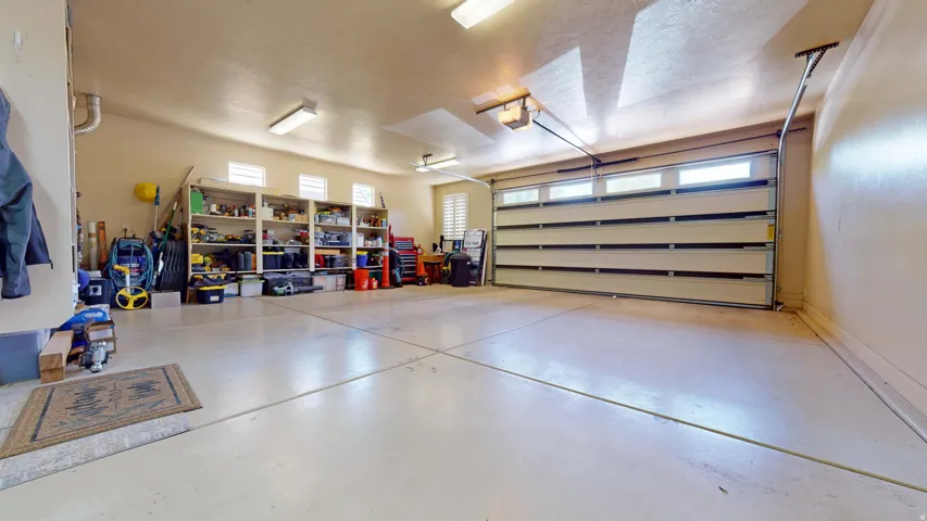 Spacious garage with multiple built-in storage shelves, overhead lighting, and a paneled garage door with integrated windows