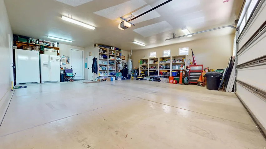 Spacious garage with multiple overhead lights, built-in shelving, and transom windows