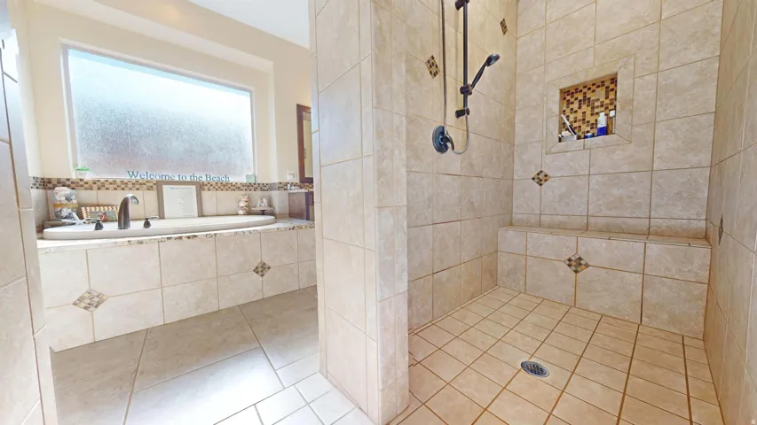 Tiled walk-in shower with a built-in bench, recessed shelf, and dark bronze shower fixtures