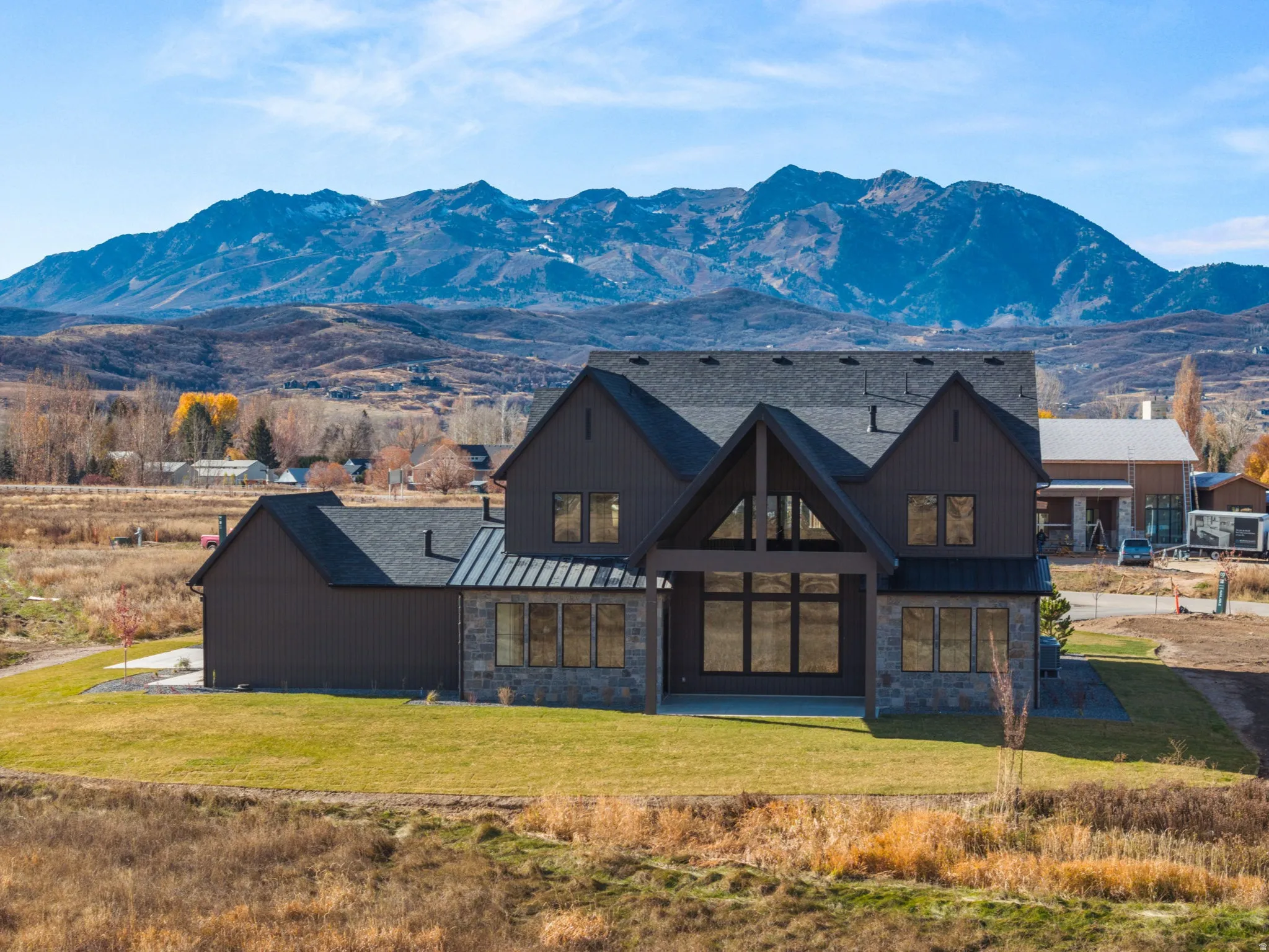 Contemporary two-story residence featuring a dark vertical board-and-batten siding facade and a stone-clad foundation