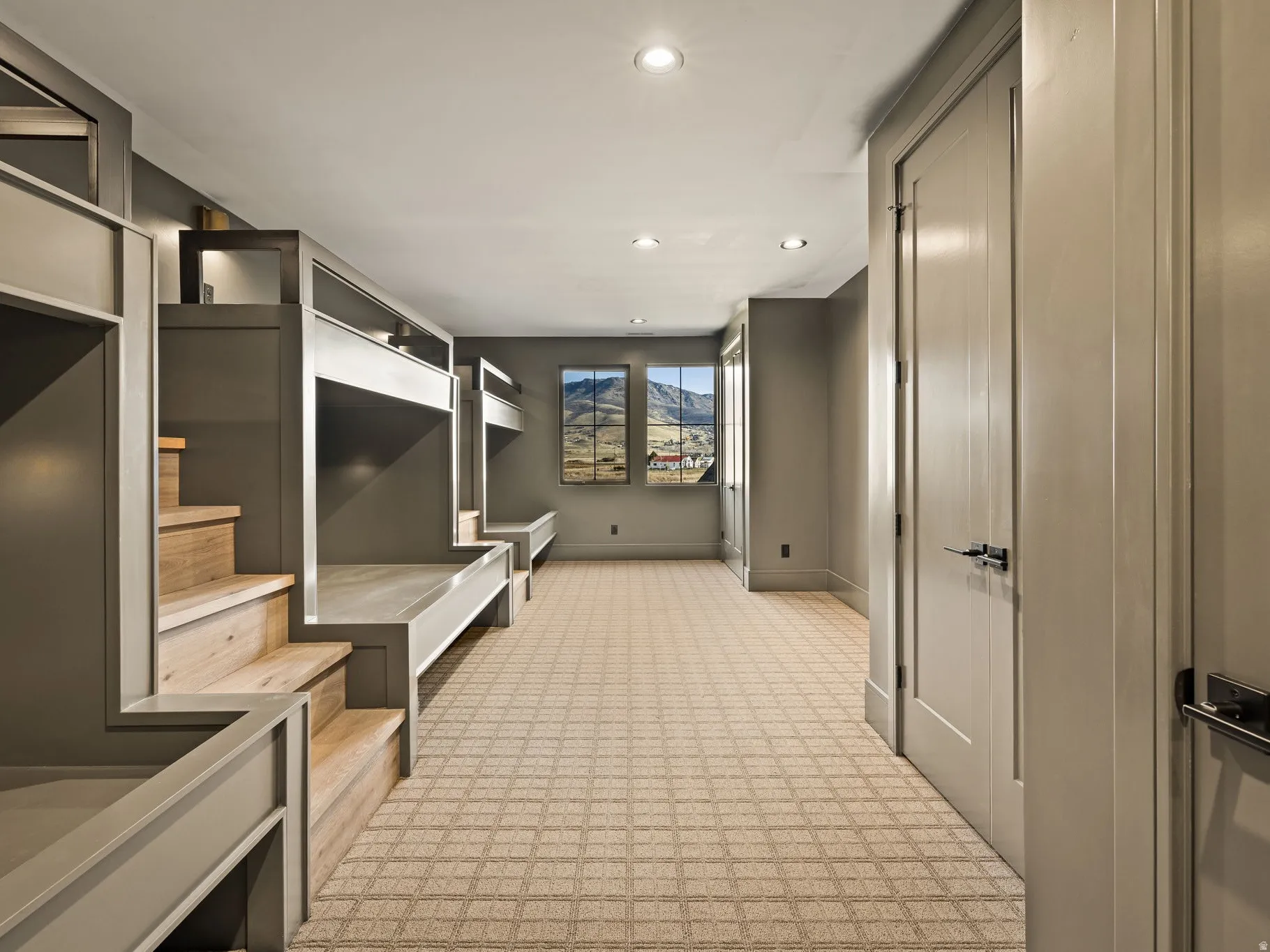 Built-in bunk beds with natural wood steps, recessed lighting, patterned carpeting, and multiple doors with dark hardware