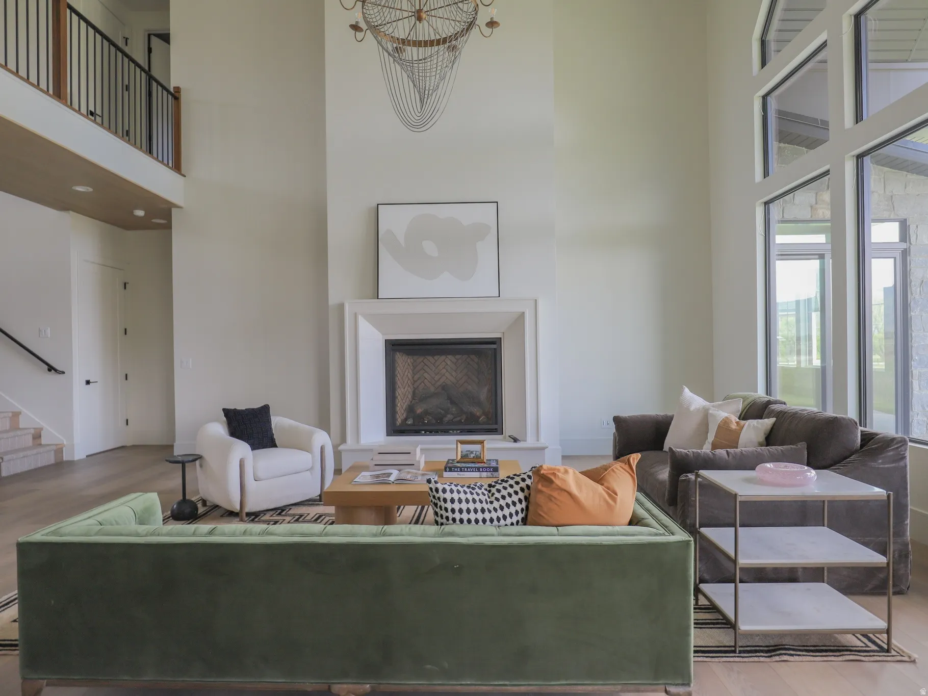 Spacious living area featuring a prominent fireplace with a substantial mantel, towering windows, and a high ceiling