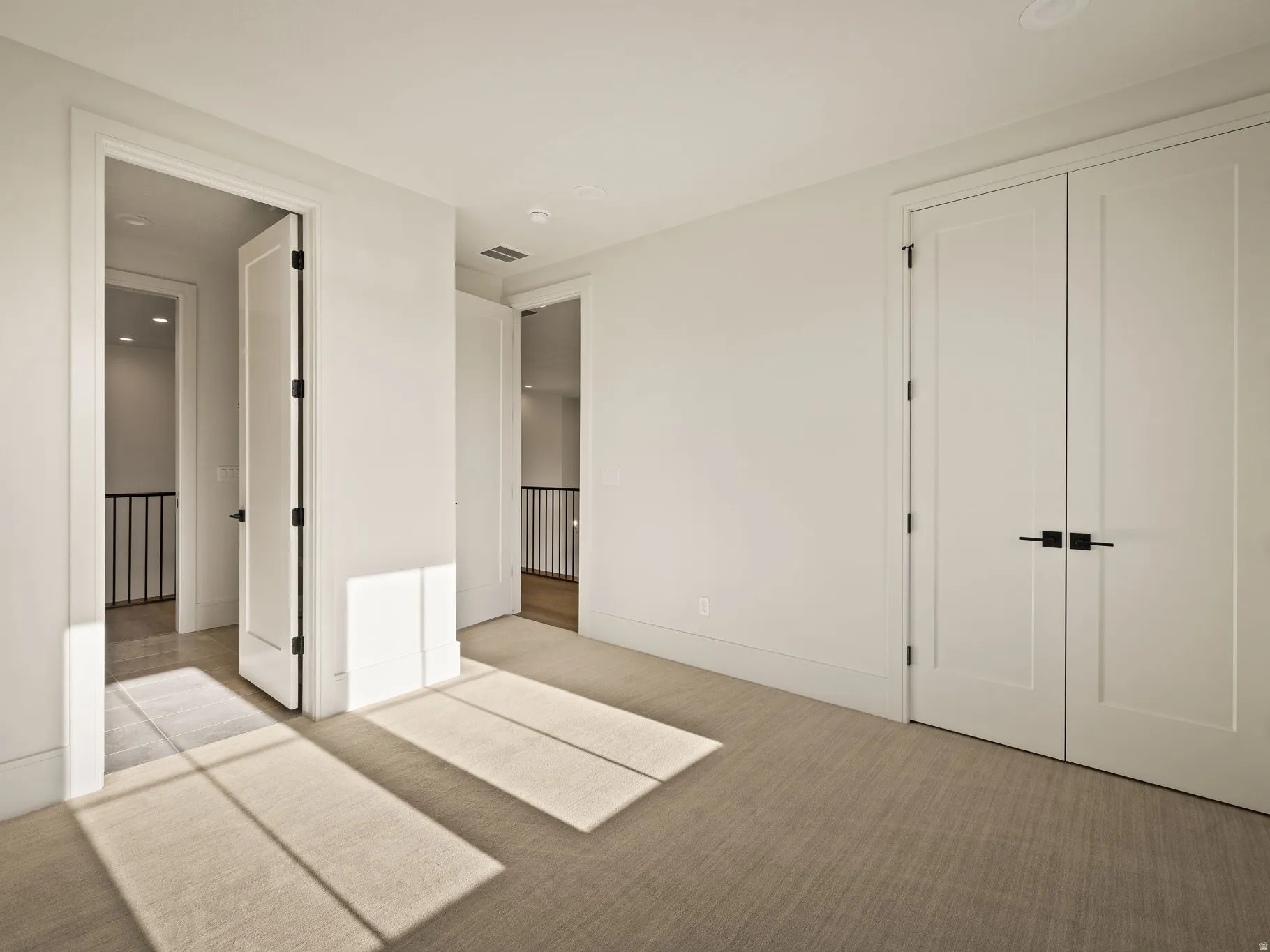 Neutral tone carpeted room with white walls, baseboards, and door frames