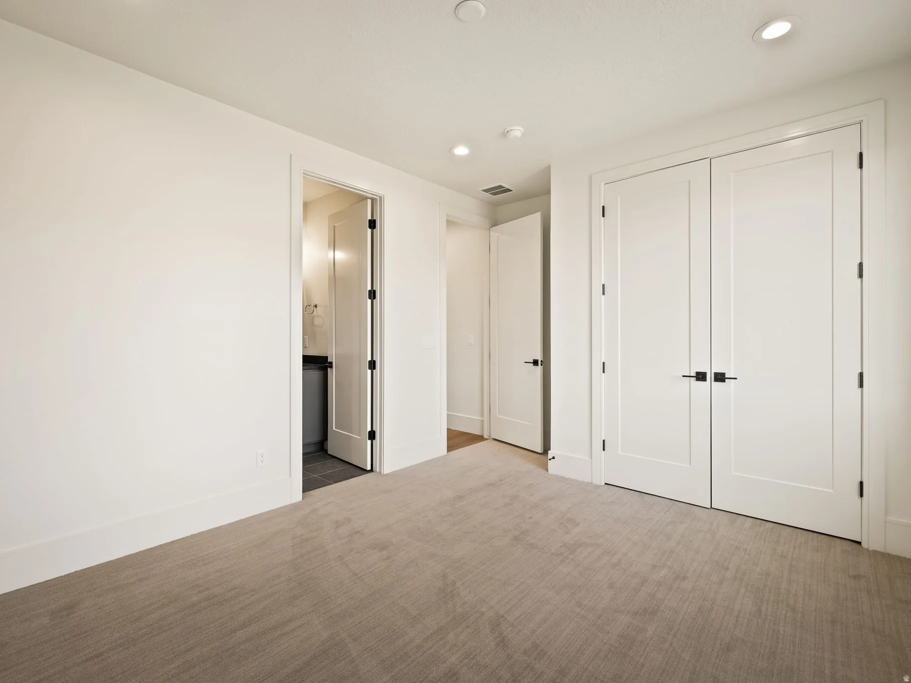 Neutral tone carpeted flooring with white baseboards