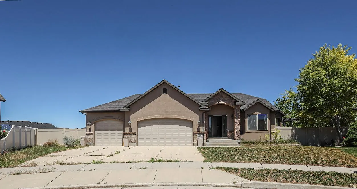 Stucco exterior with stone accents, a dual garage, and a covered entry