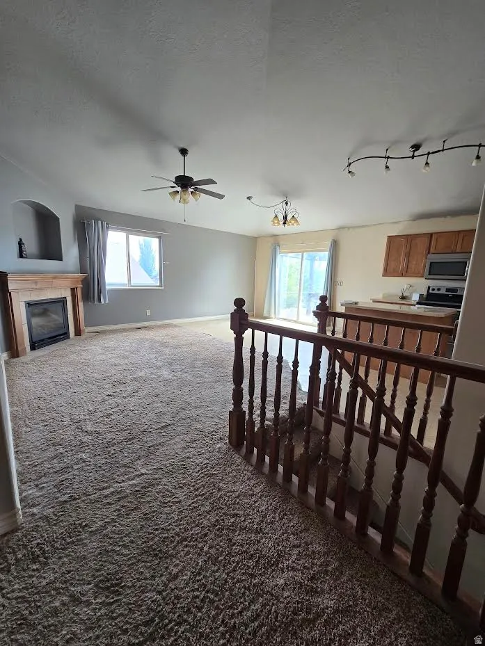 Expansive living area featuring plush carpeting and a gas fireplace with a wooden mantel