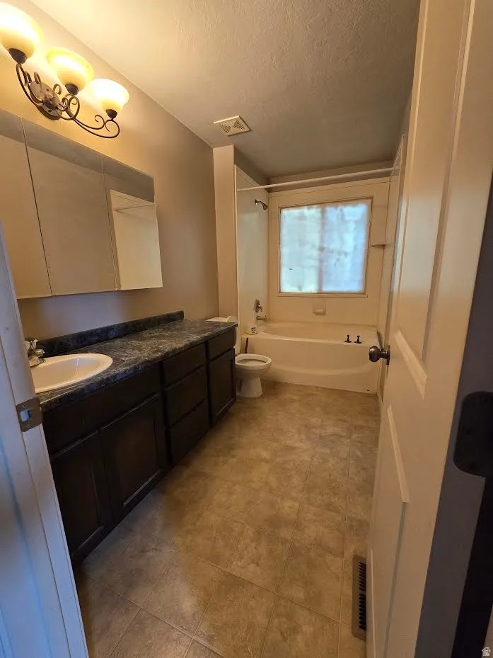 Bathroom featuring a dark wood-finish vanity with a single basin sink and a stone-look countertop