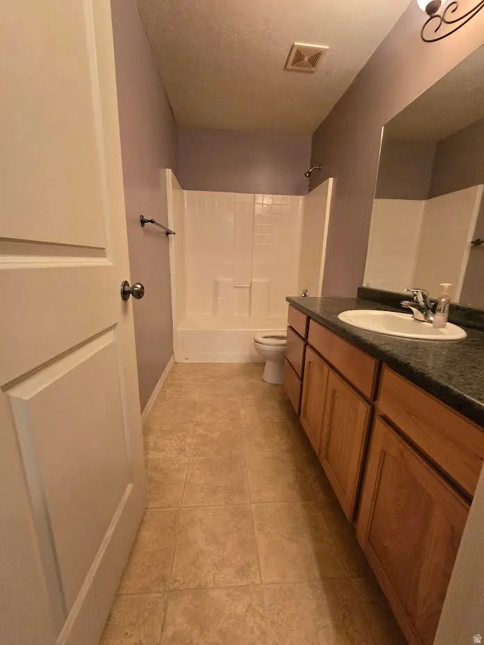 Bathroom featuring a vanity with wood-finish cabinetry, a dark countertop, and an integrated sink basin