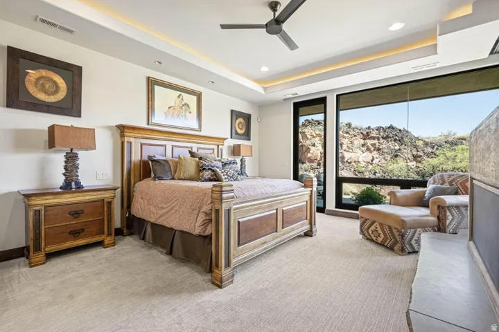 Spacious bedroom featuring large format window panels, recessed ceiling lighting, a contemporary ceiling fan, and a built-in stone fireplace hearth