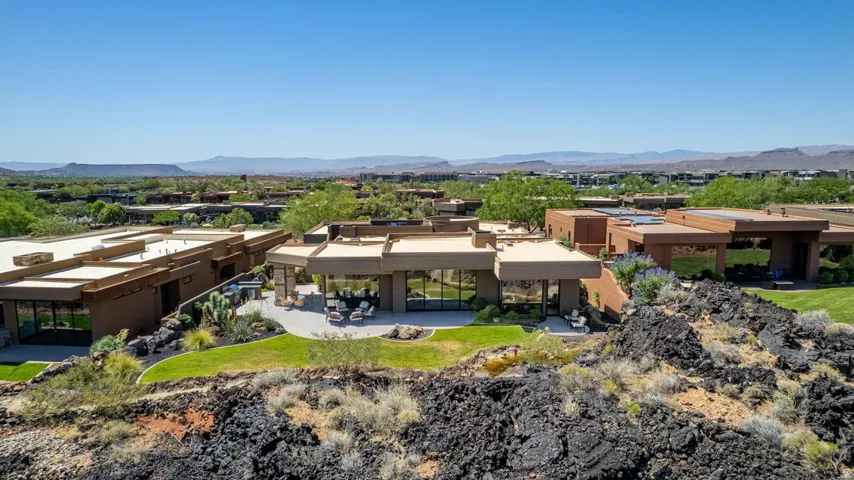 Modern architectural residence featuring a spacious patio, extensive glazing, and structured landscaping