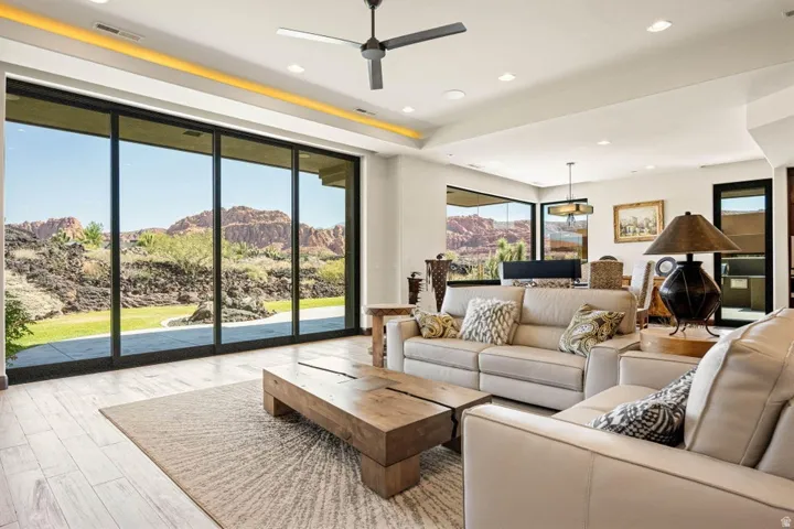 Spacious living area featuring expansive sliding glass doors, light-colored plank flooring, recessed ceiling lighting, and a contemporary ceiling fan