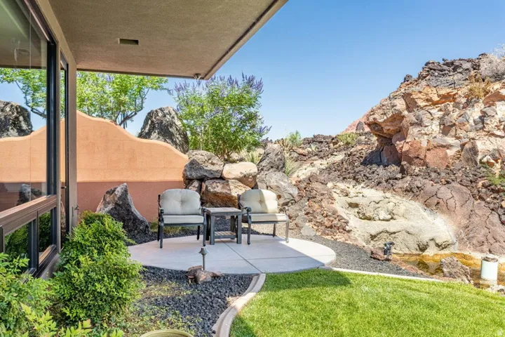 Circular concrete patio with black rock landscaping and integrated planting beds