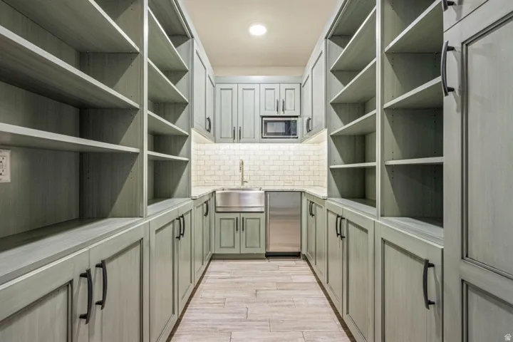 Dedicated pantry featuring extensive built-in shelving, lower cabinetry, and a full-size sink