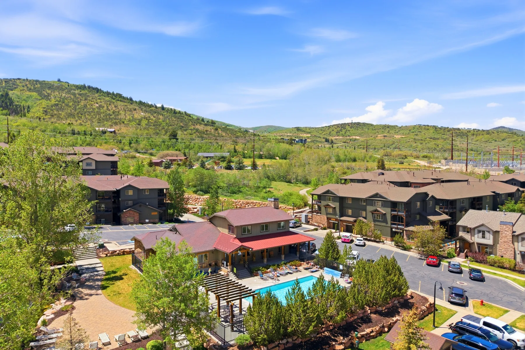 Expansive community grounds featuring an outdoor swimming pool, covered patio, and lush landscaping