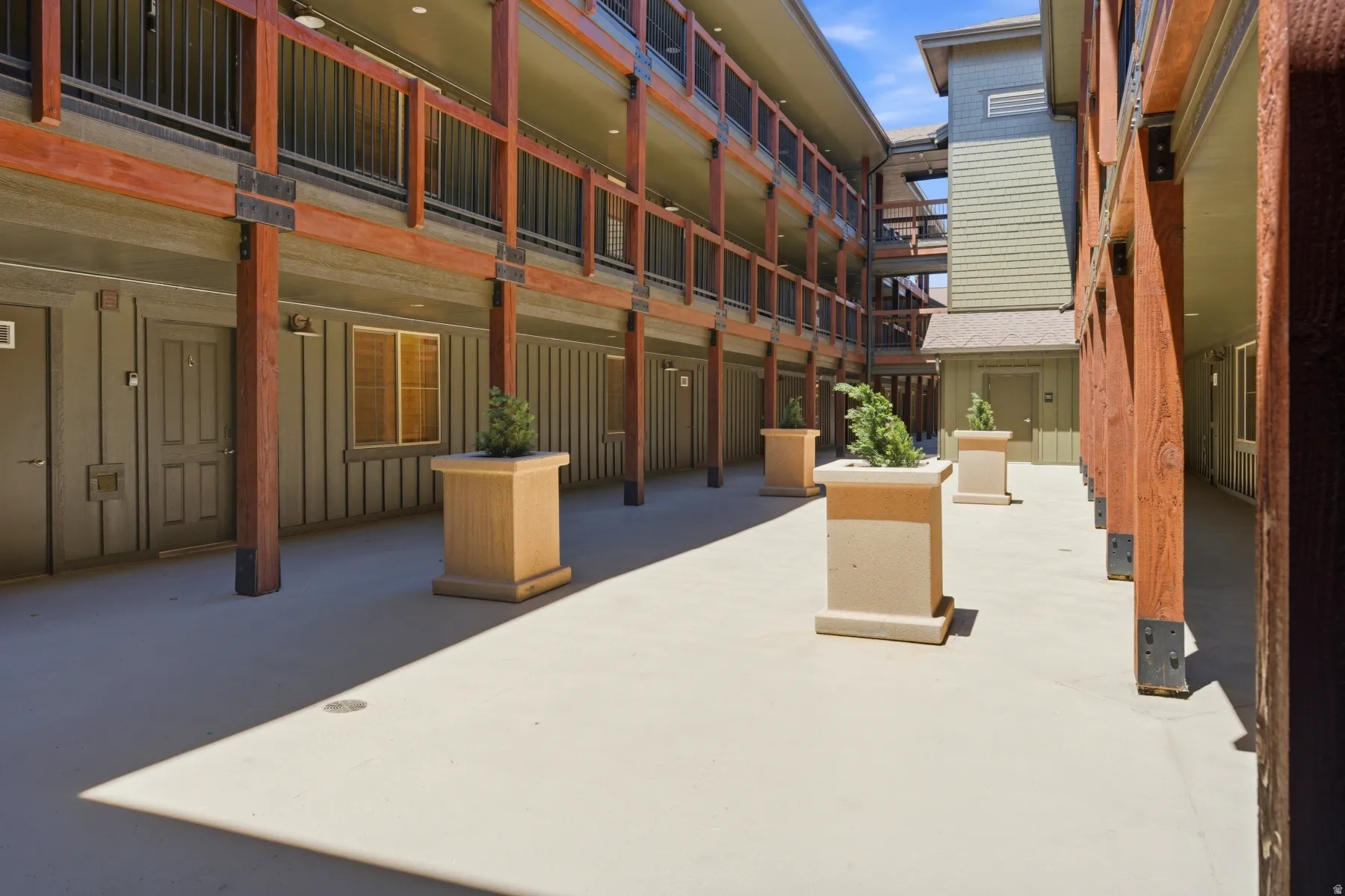 Multi-story building exterior featuring vertical wood siding and a concrete walkway