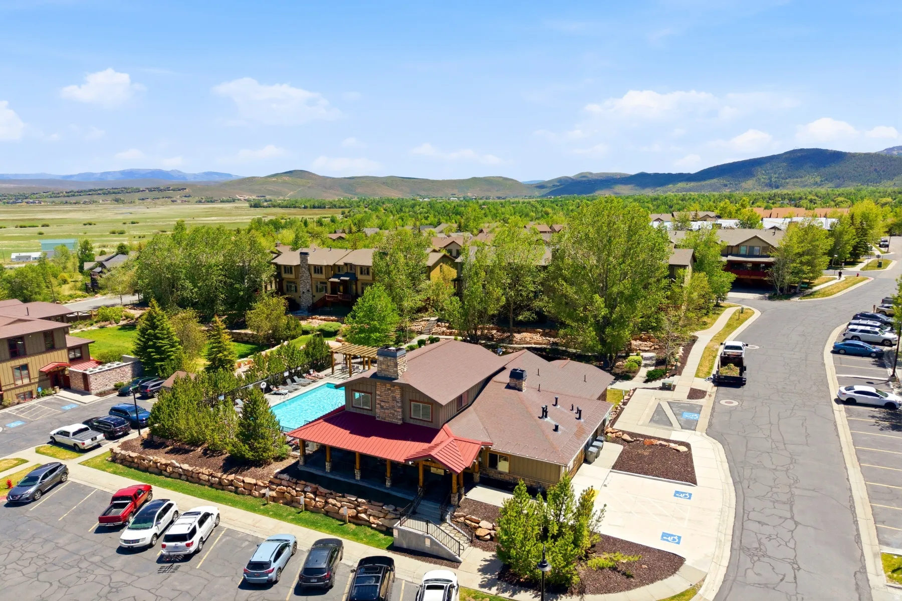 Community clubhouse featuring a covered porch, outdoor swimming pool, and stone accents