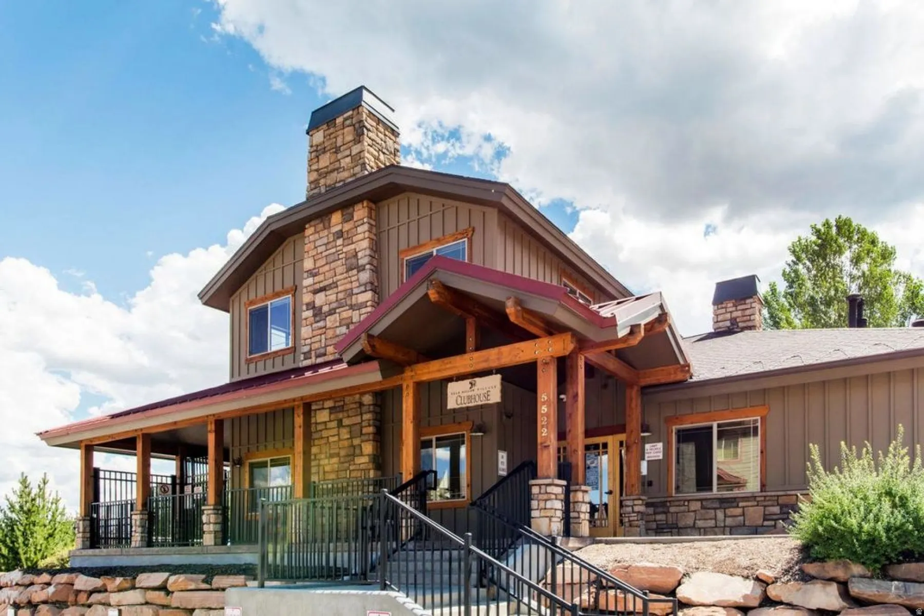 Rustic stone and wood-paneled exterior featuring a covered porch with dark railings