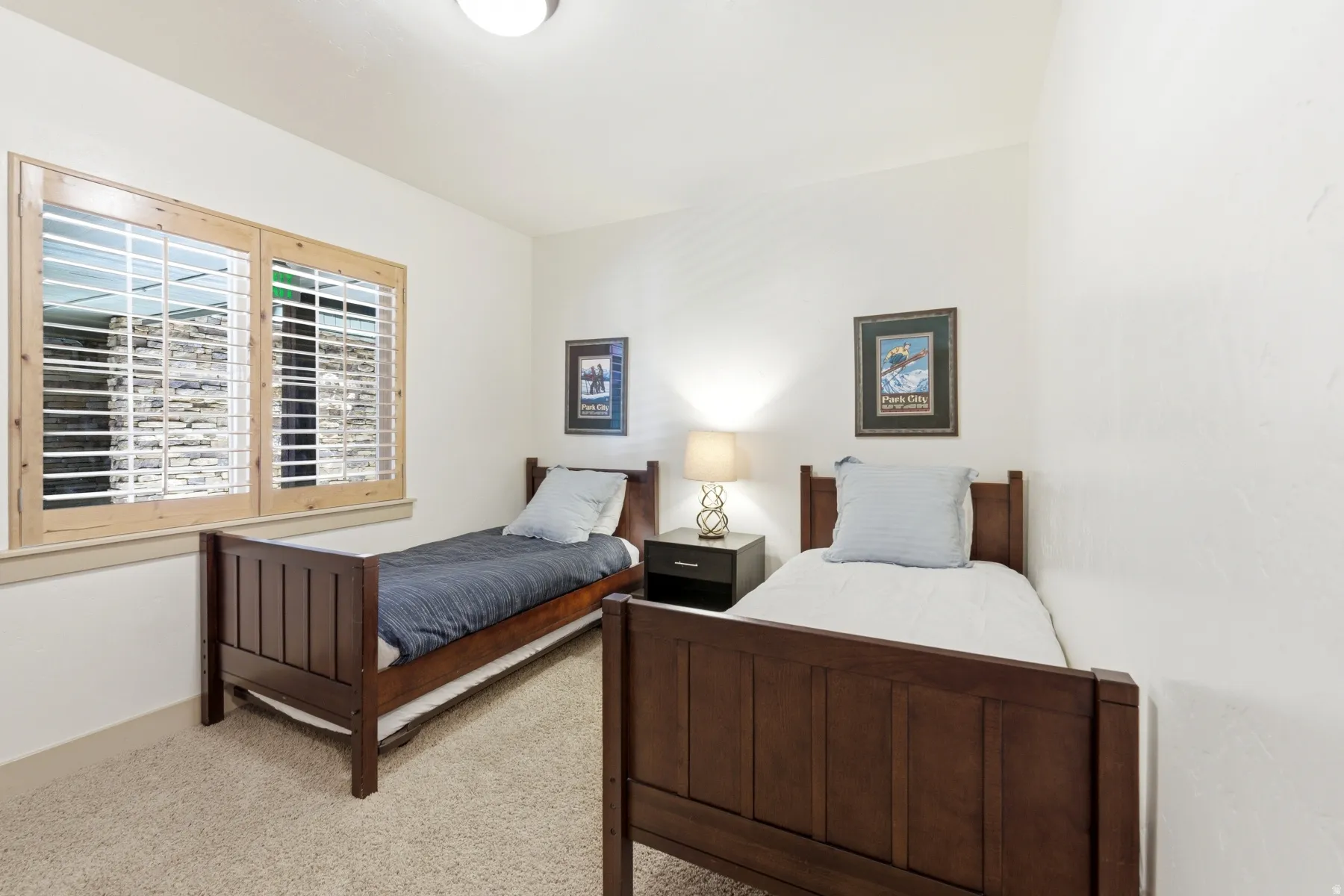 Carpeted room with a double window featuring natural wood plantation shutters, light-colored walls, and a recessed ceiling light