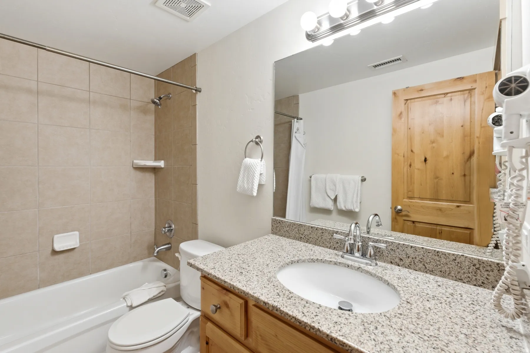 Bathroom featuring a full vanity with an undermount sink, granite-finish countertop, and wood cabinetry