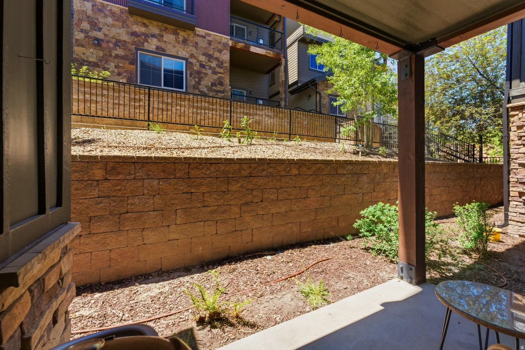 Covered patio featuring a concrete slab and stone retaining wall
