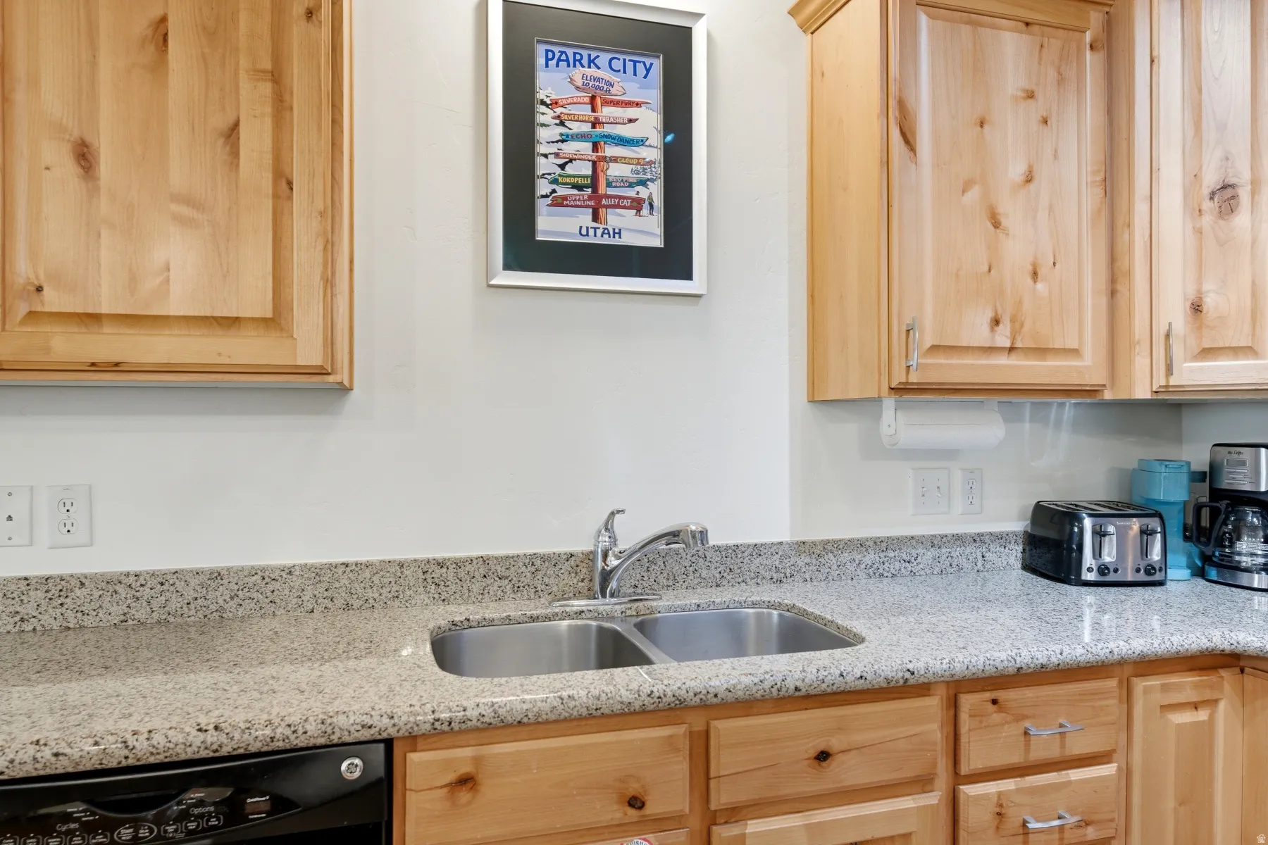 Dual basin stainless steel sink with a chrome faucet, set into a speckled countertop