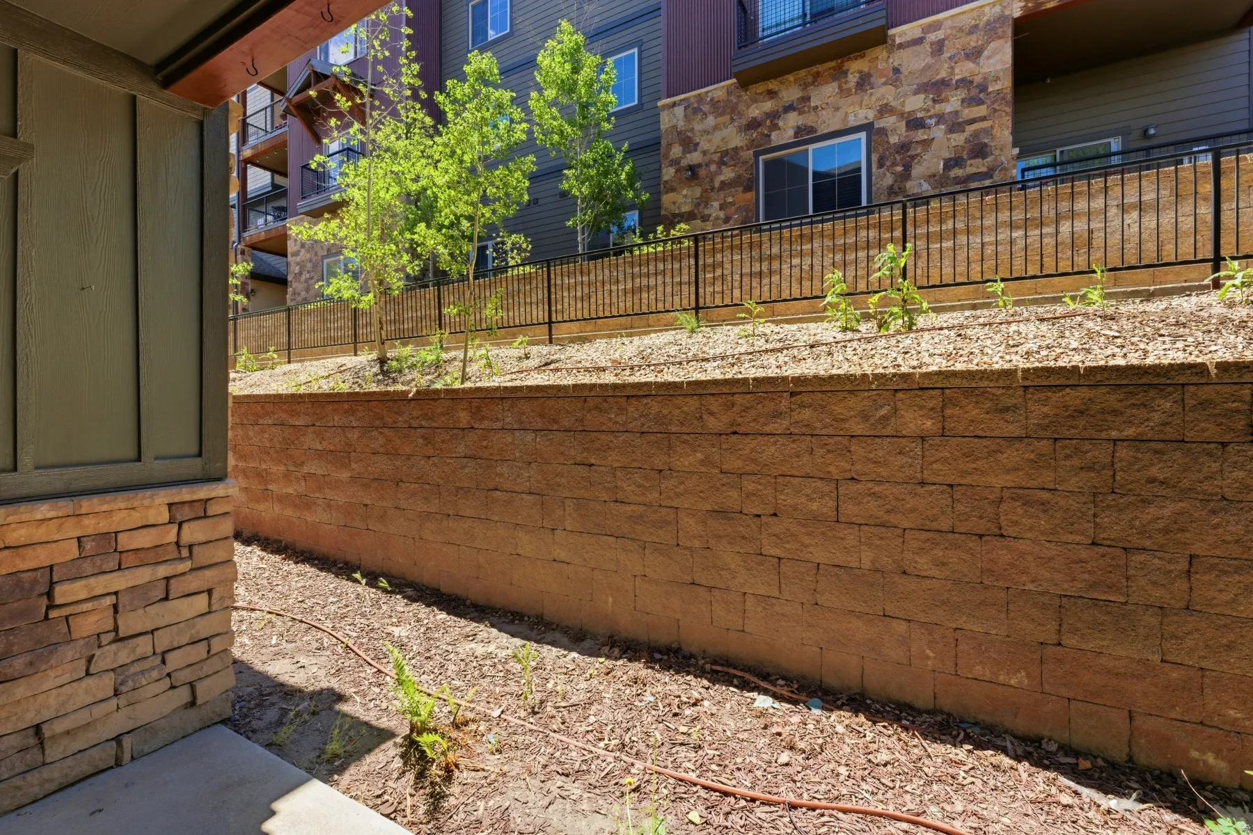 Landscaped retaining wall with block construction and a gravel and mulch planting area