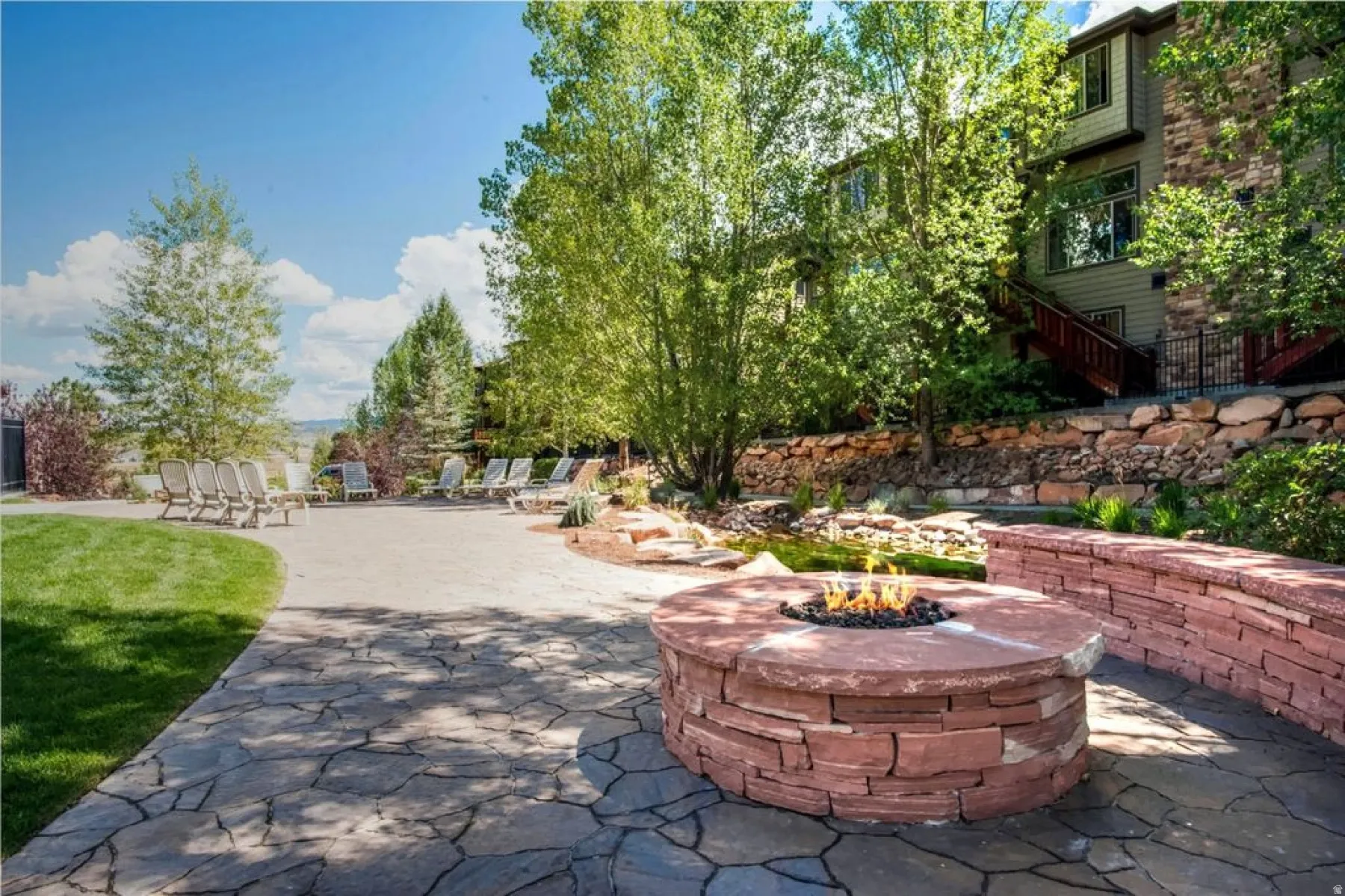 Outdoor living space featuring a flagstone patio, built-in stone fire pit, and stone retaining walls