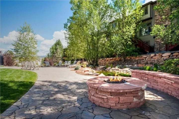 Outdoor living space featuring a flagstone patio, built-in stone fire pit, and stone retaining walls