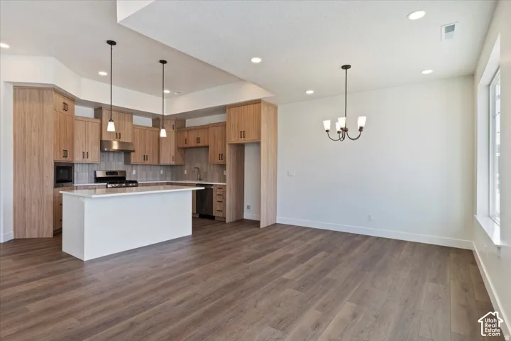 Open-concept kitchen and dining area featuring wood-finish flooring, recessed lighting, and a kitchen island with pendant lights