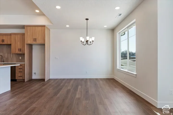 Open-concept living space featuring wood-finish flooring, recessed lighting, and a contemporary chandelier