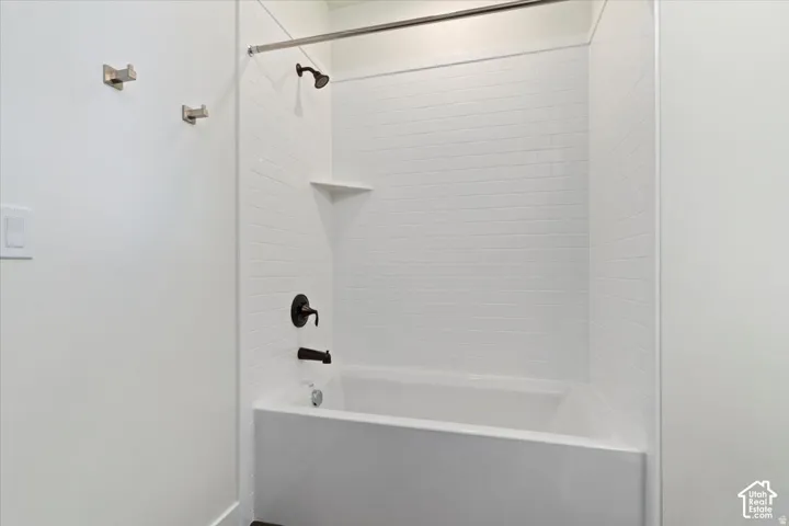 Bathtub and shower combination featuring white subway tile surround, matte black fixtures, and a chrome shower rod