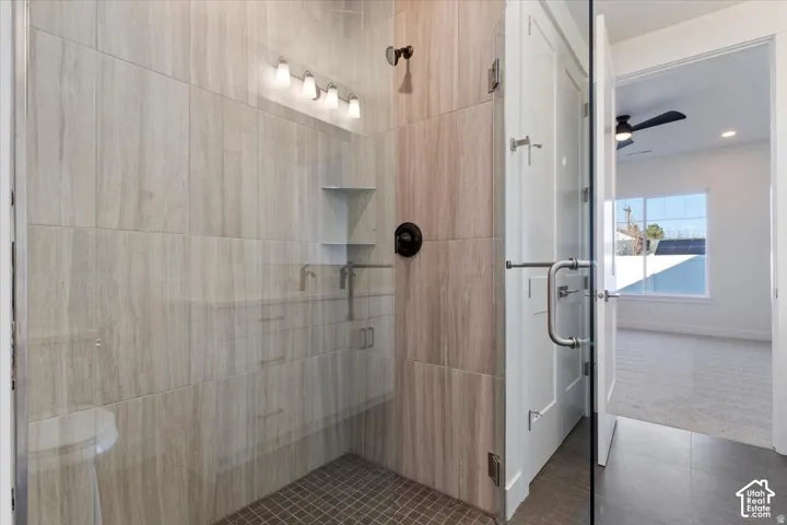 Glass-enclosed shower with full-height tile surround, dark bronze fixtures, and integrated shelving