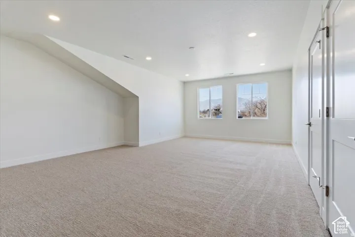 Spacious room featuring neutral carpeting, recessed ceiling lighting, and twin windows