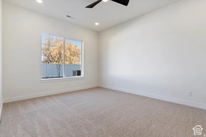 Bright interior space featuring a large window, neutral carpeting, recessed lighting, a ceiling fan, and white baseboards