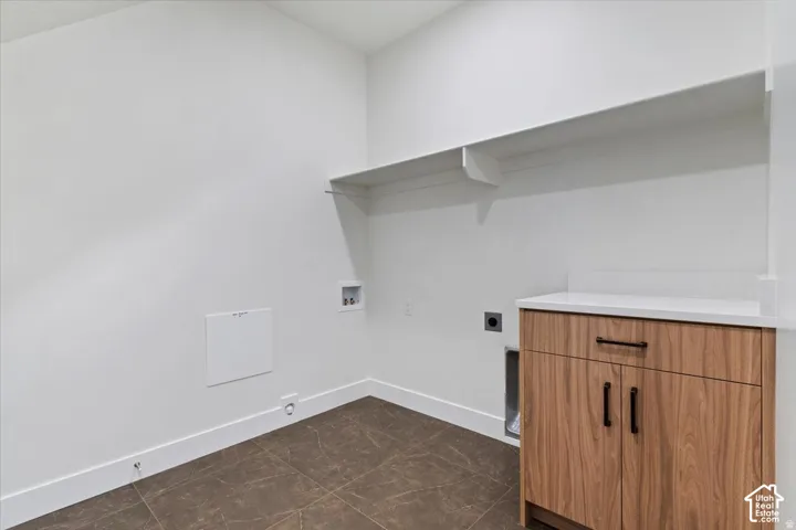 Utility space featuring a wood-finish cabinet with black hardware, white countertop, built-in shelving, and tile flooring