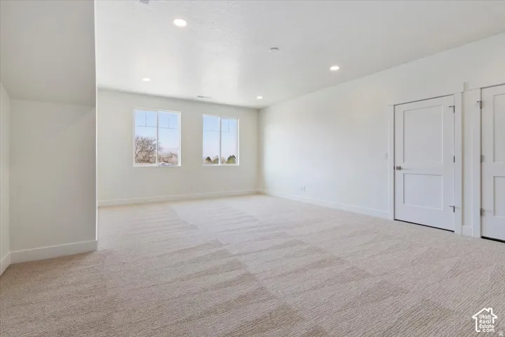 Spacious room featuring neutral carpeting, recessed ceiling lighting, and two contemporary windows