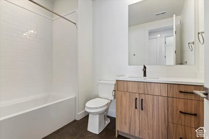 Bathroom featuring a wood-finish vanity with ample storage, a white countertop, and a rectangular undermount sink