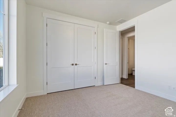 Room with neutral-toned carpet, white walls, and a large window featuring a white sill and trim