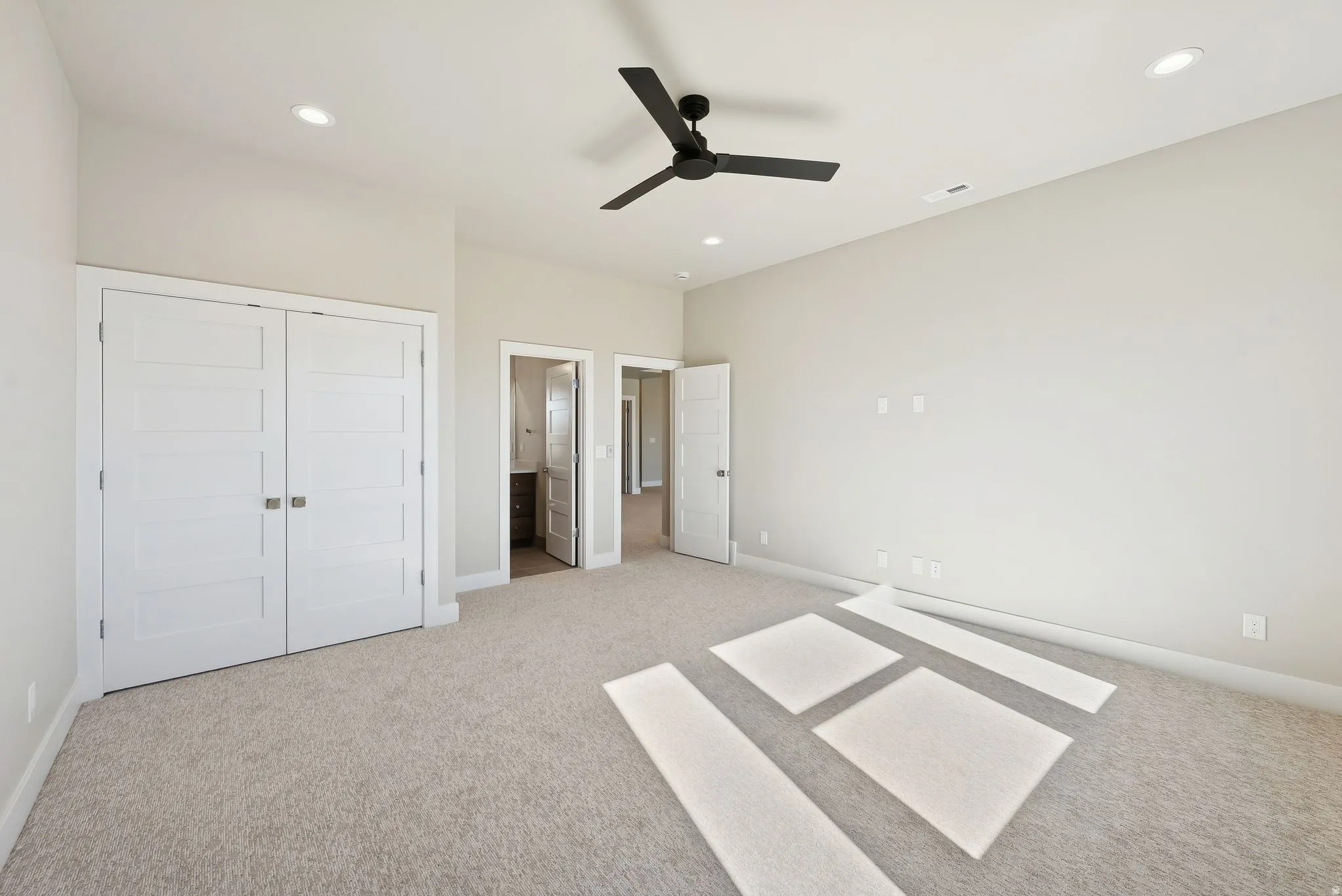 Spacious room featuring neutral carpeting, recessed lighting, and a modern black ceiling fan