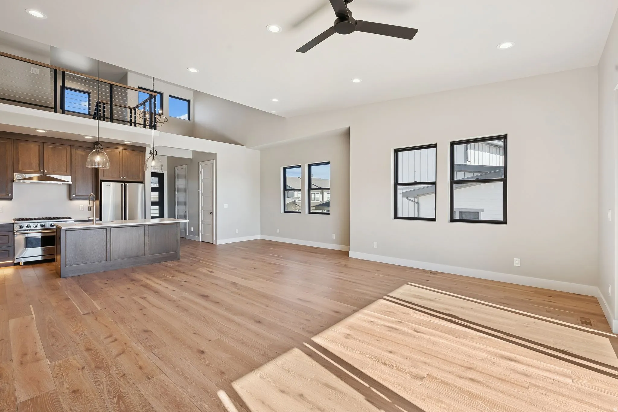 Open-concept living space featuring wood-finish flooring, a contemporary kitchen, and a vaulted ceiling