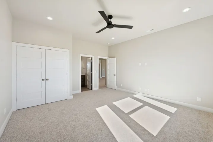Spacious room featuring neutral carpeting, recessed lighting, and a modern black ceiling fan