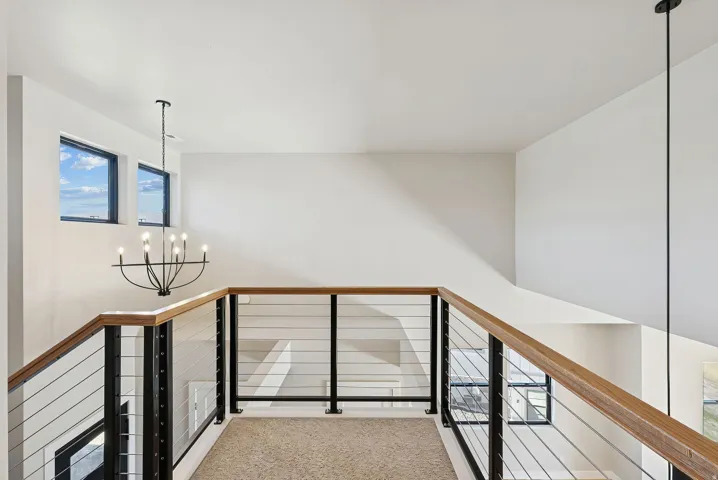 Loft area featuring a modern cable railing system with wood-finish handrails and black metal posts