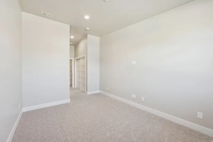 Spacious room featuring light-toned carpeting, white baseboards, and neutral wall paint