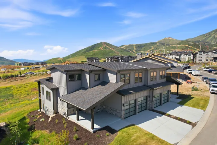 Modern multi-story property featuring a gray vertical siding exterior and stone accents