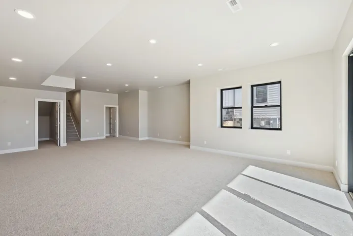 Expansive room featuring light-toned carpeting, recessed ceiling lighting, and a neutral wall color